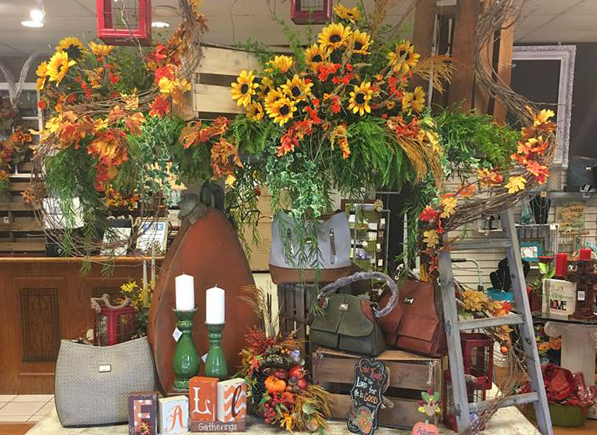 Bright daisies in hanging planters, above a display of furnishings and antiques